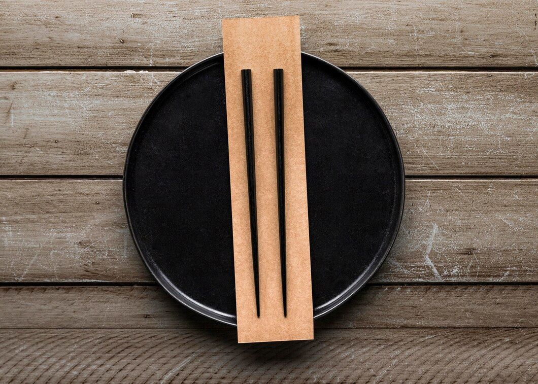 Black chopsticks resting on a black plate