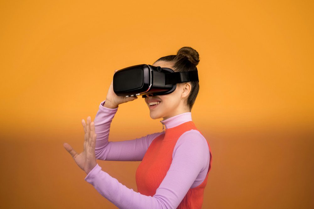 Women using a virtual reality headset in front of an orange background